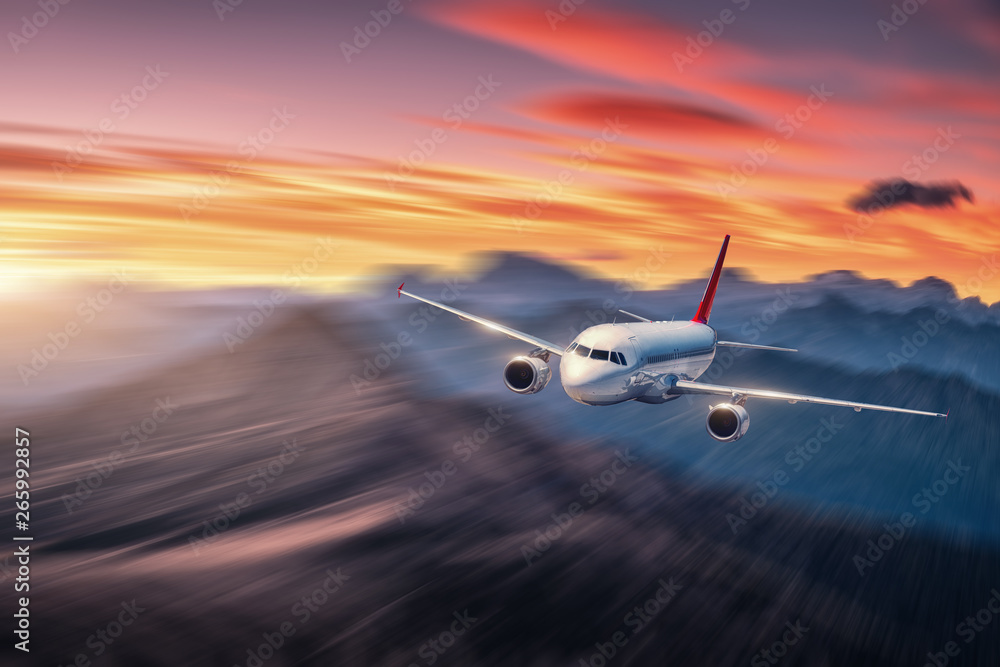 Airplane in motion. Aircraft with motion blur effect is flying over hills and mountains at sunset. Passenger airplane, blurred clouds. Passenger aircraft in motion. Business travel. Commercial.Concept - obrazy, fototapety, plakaty 