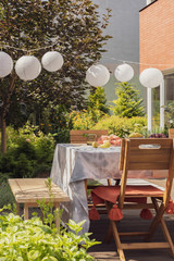 Wall Mural - Real photo of lamps hanging in a garden above a table and chairs