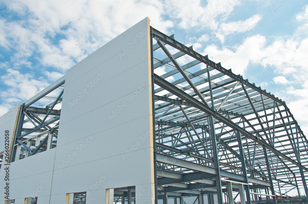 Metal frame of the building with a sandwich panel of insulation on the wall. Construction of a new industrial building. - obrazy, fototapety, plakaty 