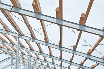 Poster - Metal frame of the new building with laid wooden beams fore roof. The fast-built designs from metal.