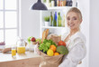 © lenetsnikolai - Young woman holding grocery shopping bag with vegetables Standi