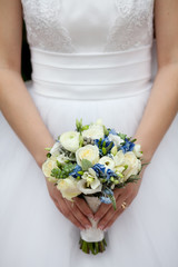 Wall Mural - Charming wedding bouquet of white roses and freesias with blue flowers in the hands of an unrecognizable bride