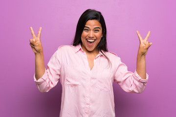 Wall Mural - Young Colombian girl over purple wall showing victory sign with both hands