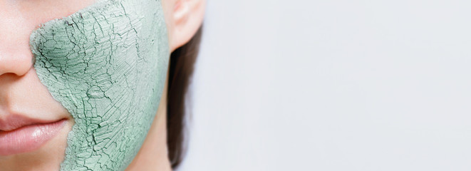 Wall Mural - Model woman with healthy glow perfect smooth skin. Young girl enjoys facial mask. Skincare, beauty, cosmetology concept. Closeup view of cracked texture  green clay mask.