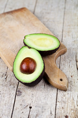 Canvas Print - Fresh organic avocado halves on cutting board on old wooden table background.