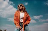 Fototapeta Tulipany - High fashion portrait of stylish beautiful woman in trendy jackets and jeans posing outdoor. Vogue style.