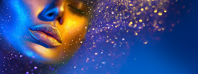 Wall Mural - Fashion model woman face in bright sparkles, colorful neon lights, beautiful sexy girl lips. Trendy glowing gold skin make-up. Glitter metallic shine makeup