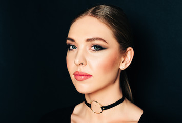 Close up portrait of beautiful young woman with dark professional make up, posing on black background