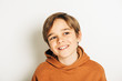 © annanahabed - Studio shot of handsome 10 year old boy with blond hair, wearing brown hoody, posing on white background, looking up
