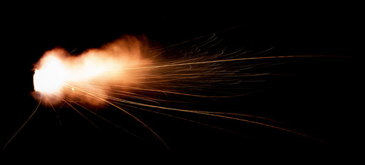 Wall Mural - Texture of firearm shot with bright flash of light, sparks, smoke and gunpowder gases on black background