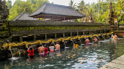 People are doing the ritual purifying bath at Tirta Empul temple, a Hindu Balinese water temple famous for its holy spring water, in Bali, Indonesia.