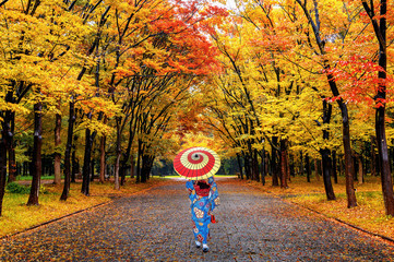 Asian woman wearing japanese traditional kimono walking in autumn park.