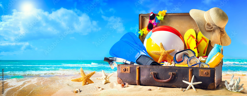 Beach accessories in suitcase on sand. Family holidays concept - obrazy, fototapety, plakaty 