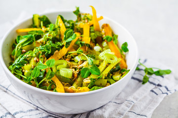 Wall Mural - Green salad with spinach, pepper, cucumber, pesto sauce and sprouts in white bowl.