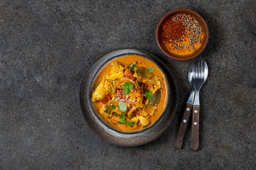 INDIAN FOOD. Traditional KERALA FISH CURRY with naan bread, gray plate, black background 