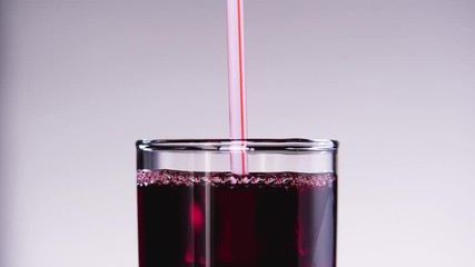 Wall Mural - Someone drinking cherry or strawberry juice from the glass throw the straw.