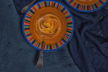 Wall Mural - Bowl of pumpkin organic soup with cream and pumpkin seeds on gray background. Dietary vegetarian food. Concept of healthy eating food. Homemade autumn soup. Top view with copy space. Toned image.