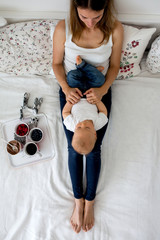 Canvas Print - Mother and toddler baby boy, lying in bed, hugging with love, high angle shot, from above