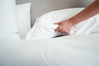 © Suphansa - Female Hand set up white bed sheet in room hotel