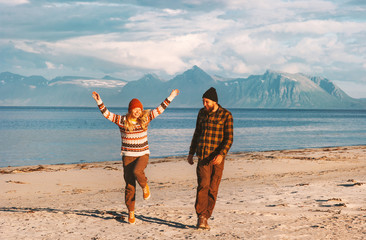 Wall Mural - Happy couple traveling together joyful walk on beach in Norway man and woman lifestyle summer vacations outdoor
