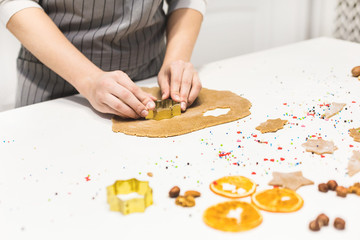 Wall Mural - Young pretty woman prepares the dough and bakes gingerbread and cookies in the kitchen. Merry Christmas and Happy New Year.