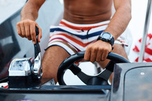 Tanned Young Handsome Captain Or Skipper Steering At The Helm And Control Panel Of A Yacht With His Hands