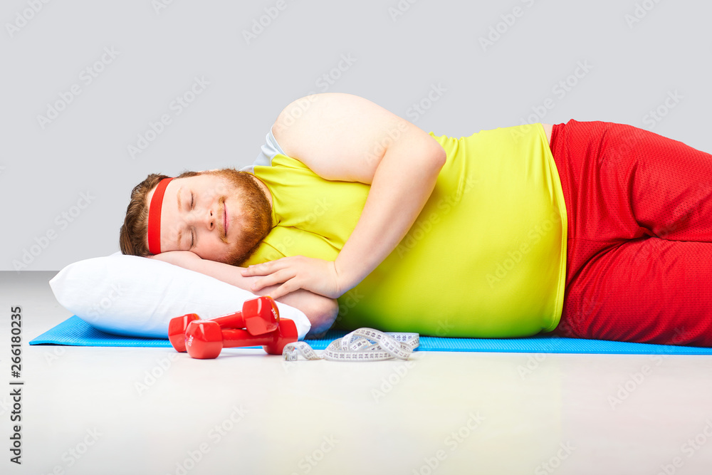 Lazy fat funny man is sleeping on a gray background. - obrazy, fototapety, plakaty 