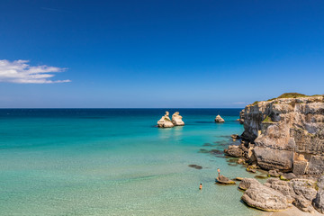 The bay of Torre dell'Orso, with its high cliffs, in Salento, Puglia, Italy. Turquoise sea and blue sky, sunny day in summer. The stacks called the Two Sisters, immersed in the sea.