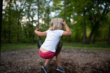 Little Girl Sitting On The Swing In The Park