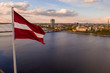 Aerial panorama of Riga city with a big Latvian flag in the foreground. Golden hour.