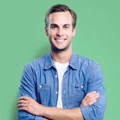 Wall Mural - Portrait of young man standing in crossed arms pose, square composition photo