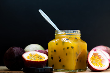 Passion fruit jam in a glass bottle on the wooden floor on a black background