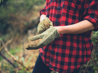 Young woman putting on gardening gloves