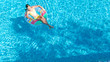 © Iuliia Sokolovska - Acrive girl in swimming pool aerial top view from above, kid swims on inflatable ring donut , child has fun in blue water on family vacation resort