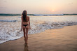 young woman in sexy swimming suit black thong in sea wawes having fun at sunset Goa beach India ocean