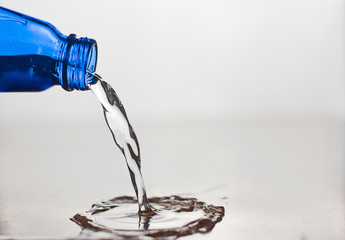 pouring water into glass.  blue water bottle. water pours from the bottle to the surface