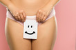 Woman holding sheet of paper with smile in front of her vagina