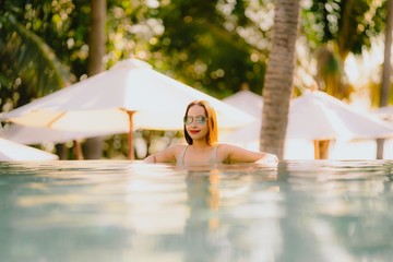 Portrait beautiful young asian woman smile happy relax around swimming pool in hotel resort for leisure