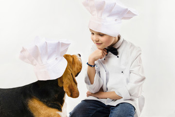 funny boy in chef uniform and cute beagle dog in chef's cap cook dinner