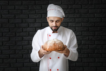 Poster - Chef with fresh bread on dark background