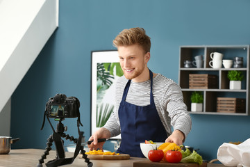 Wall Mural - Young male food blogger recording video in kitchen