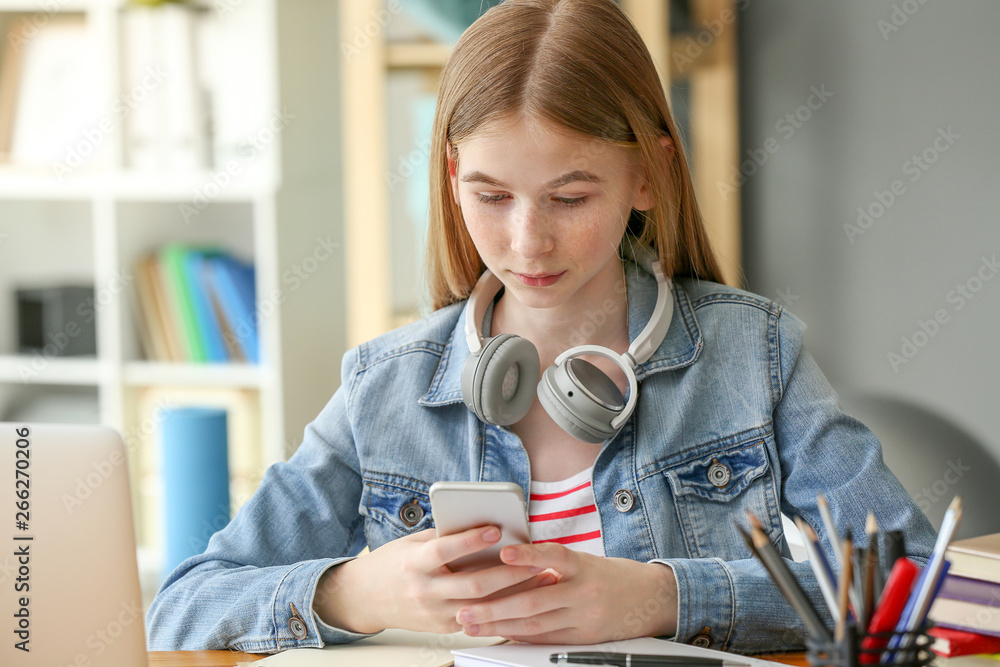 Cute teenage girl using mobile phone at home