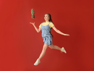 Wall Mural - Jumping woman with pineapple on color background