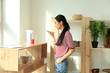 © Pixel-Shot - Young Asian woman with mobile phone in kitchen. Modern technology and smart home automation