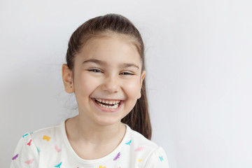 Portrait of happy smiling child girl on light background. Laughing people. Positive emotions.