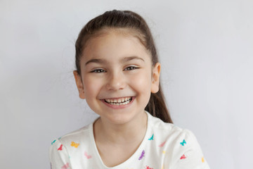 Portrait of happy smiling child girl on light background. Laughing people. Positive emotions.