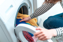 Loading Colored Clothes And Linen In Washing Machine. Doing Laundry At Home