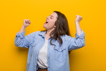 Wall Mural - Young curvy plus size woman raising fist after a victory, winner concept.