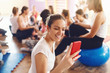 © dusanpetkovic1 - Group beautiful fit of sporty women sitting in gym and using smart phones and resting after exercises. Selective focus on brunette with red smart phone.