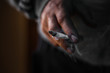 © Hanna - closeup a man's hand holding a crumpled, smoldering cigarette with smoke hand smoking cigarette ,unhealthy lifestyle concept